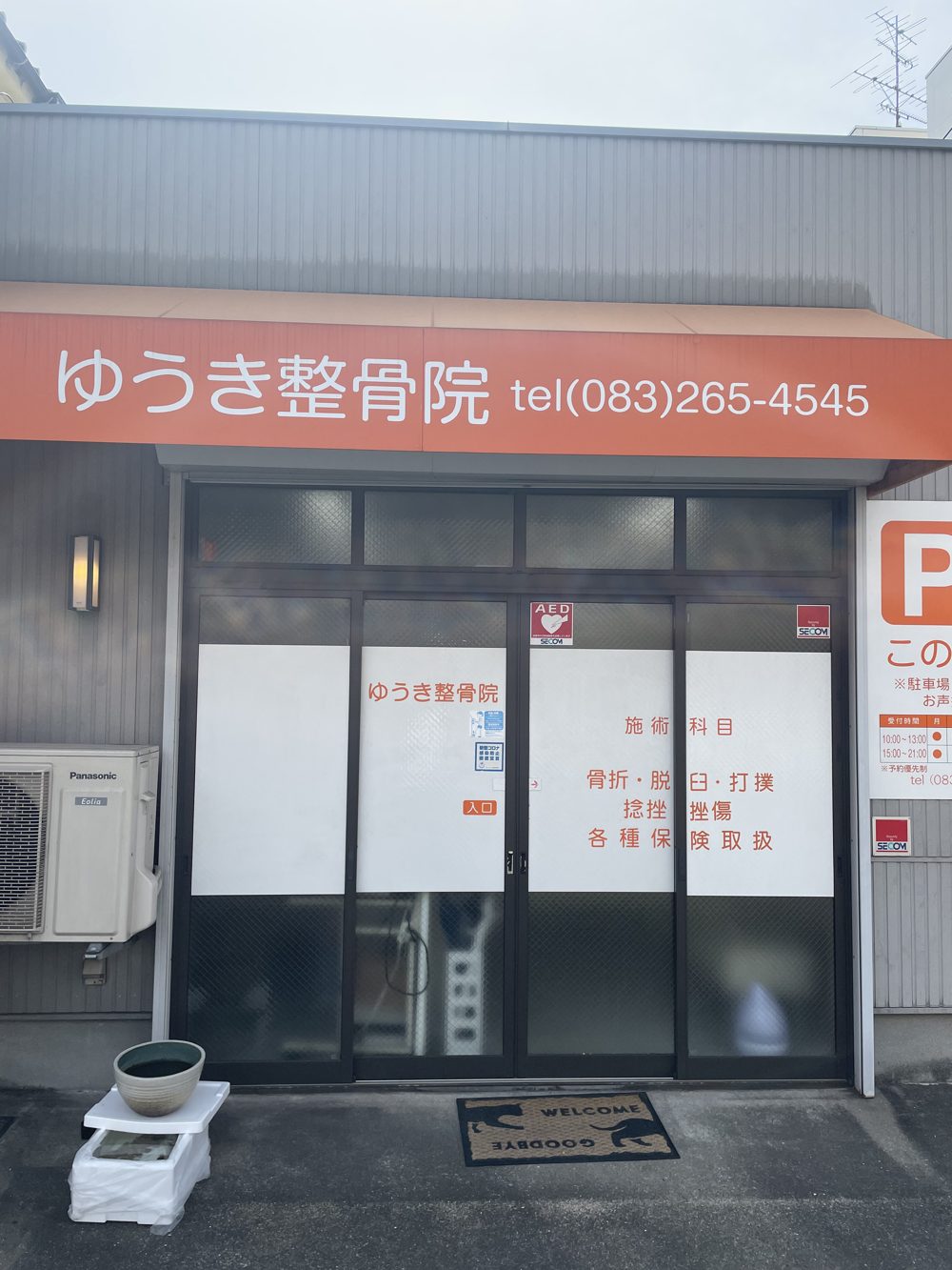 ゆうき整骨院の正面。オレンジ色の看板に院名と電話番号